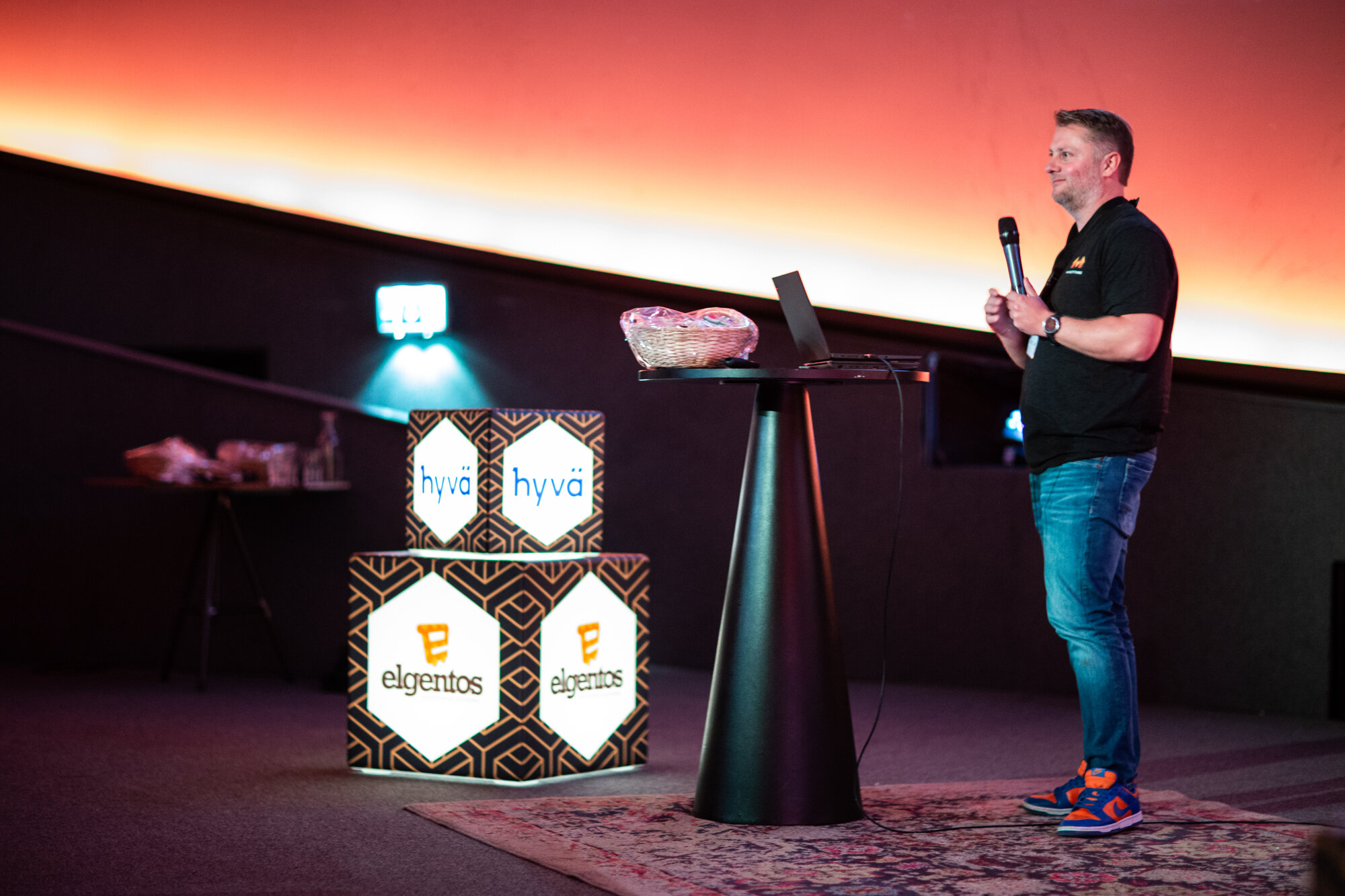 A speaker on stage at MageTitans 2024, in front of a full theatre